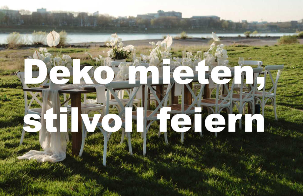 Festlich gedeckte Tafel im Freien mit weißer Blumendeko am Fluss.